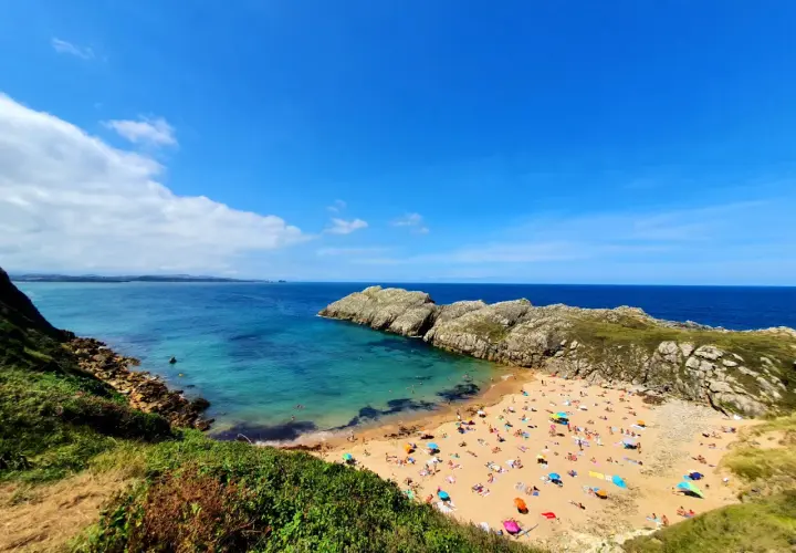 Vista aérea de la playa de Somo, con gente disfrutando del sol y el mar. Las reseñas de la playa de Somocuevas la describen como un paraíso.