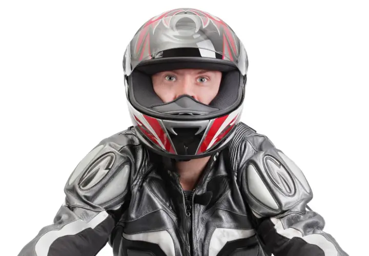 Occhi spalancati dietro un casco stretto, pronto per la corsa. La tuta in pelle grigia e nera completa il look da motociclista.