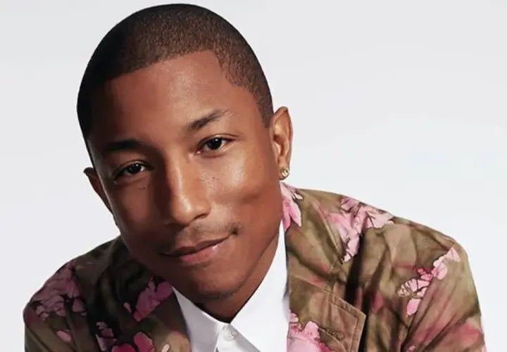 Pharrell Williams w kwiecistej marynarce, uśmiecha się, emanując pozytywną energią, jak w tekście "Happy".
