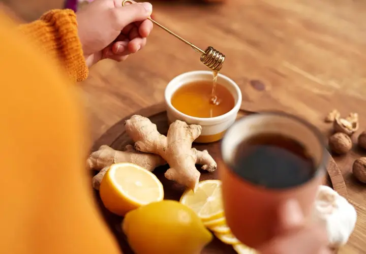 Zutaten für hustentee selber machen: Ingwer, Zitrone, Honig und eine Tasse Tee.
