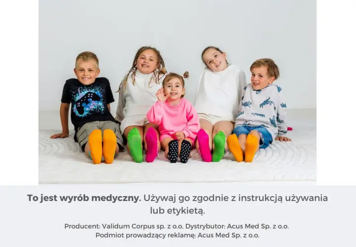 Pięcioro dzieci siedzi na podłodze, prezentując kolorowe skarpetki na stopach.