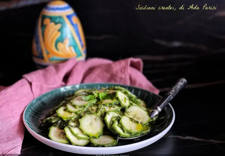 Assiette de courgettes marinées à l'italienne, garnie de basilic frais. Un plat sicilien créatif.