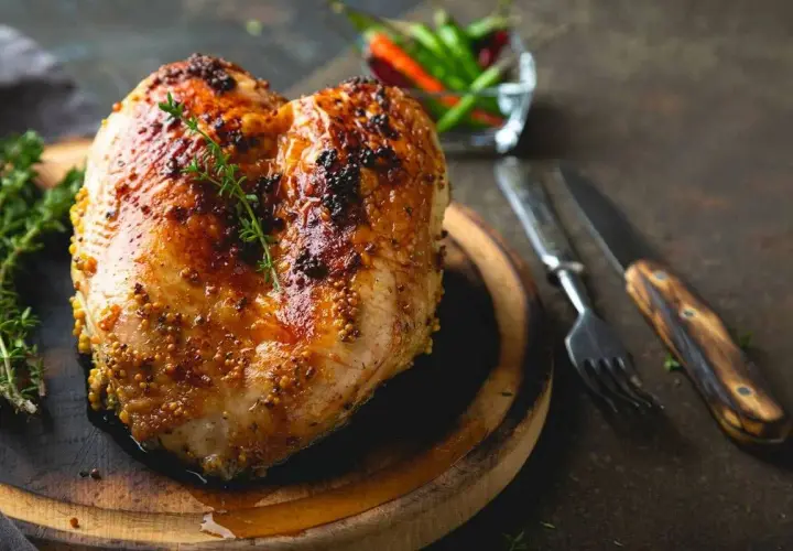 Succulento petto di pollo al forno, dorato e speziato, pronto per essere gustato con erbe aromatiche e peperoncini.
