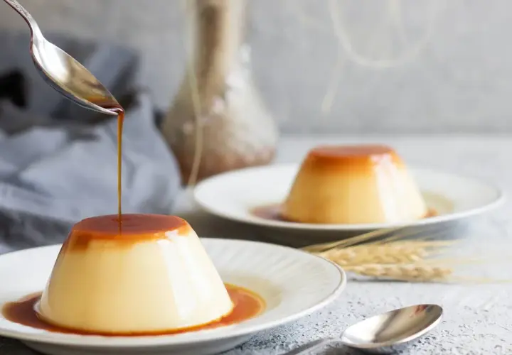 Delicioso flan de huevo con caramelo líquido cayendo de una cuchara. Una receta casera que enamora.