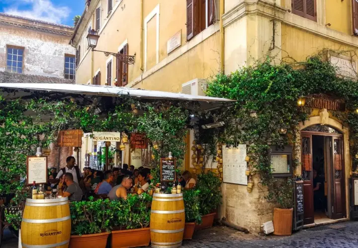 Un charmant restaurant à Rome, "Antica Osteria Rugantino", envahi par la végétation. Idéal pour savoir où manger à Rome.