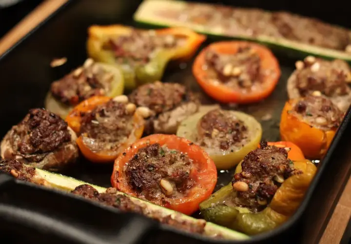 Délicieux légumes farcis, tomates, poivrons et courgettes, garnis d'une savoureuse farce à la viande et aux pignons.