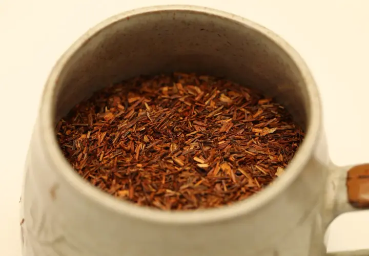 Czerwona herbata rooibos w ceramicznym kubku, idealna na relaksujący wieczór.
