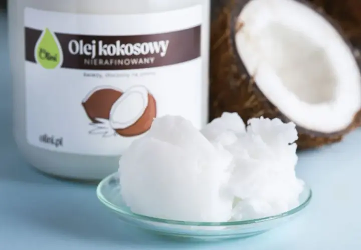 Olej kokosowy nierafinowany na talerzyku, idealny jako jaki olej do smażenia. Obok słoik i połówka kokosa.