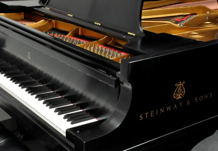 Czarne pianino Steinway & Sons z otwartą klapą, ukazującą struny i złote wnętrze. Zastanawiasz się, ile waży płyta mosiężna w pianinie?