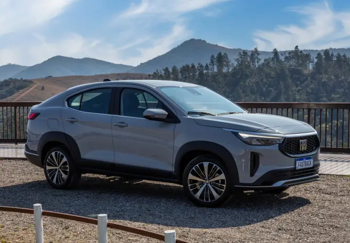 Fiat Fastback 2026 grigio metallizzato, un SUV coupé con un design audace, parcheggiato su un bel belvedere montano.