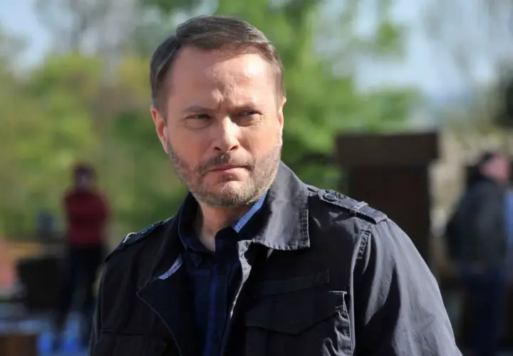 Artur Żmijewski, który gra Ojca Mateusza, w ciemnej kurtce i kratowanej koszuli, zamyślony.