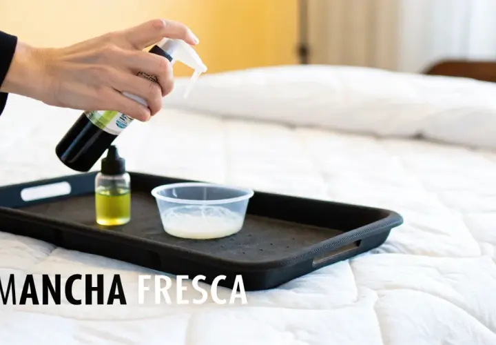 Mano rociando limpiador sobre una bandeja con líquidos, parte de un tutorial sobre como limpiar un colchon.