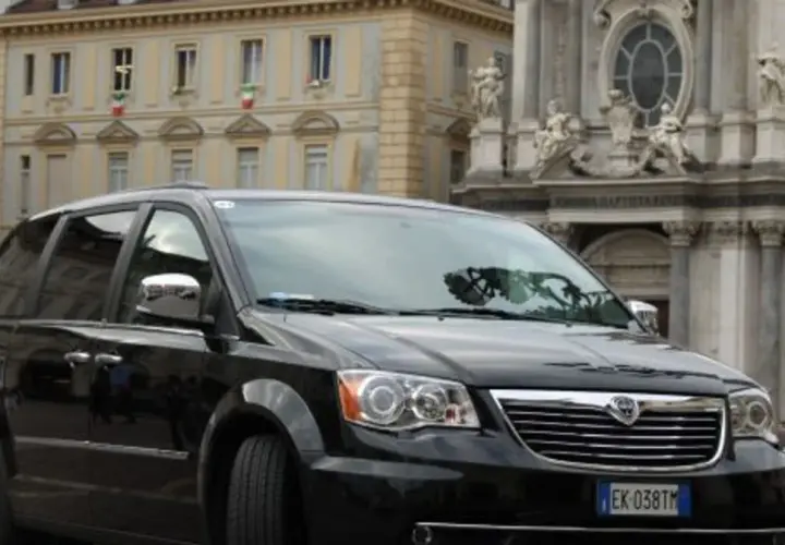 Czarny Lancia Voyager na tle zabytkowej architektury.