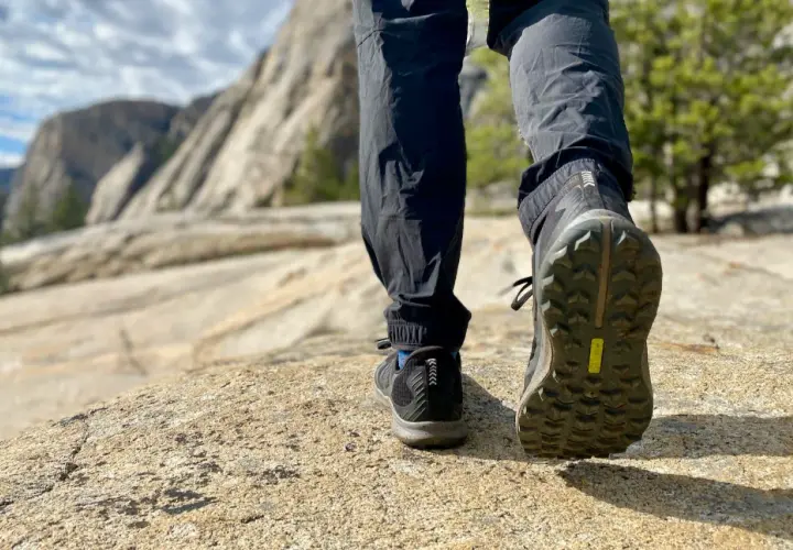 Close-up of hiking boots on a rocky trail, showcasing the aggressive boot tread patterns designed for grip on uneven terrain.