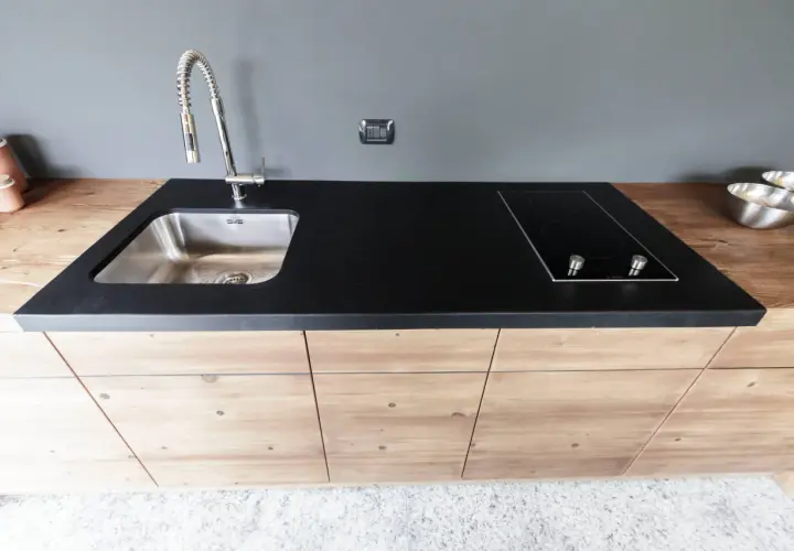 Mobile lavello cucina fai da te con piano in pietra nera, piano cottura a induzione e rubinetto cromato.