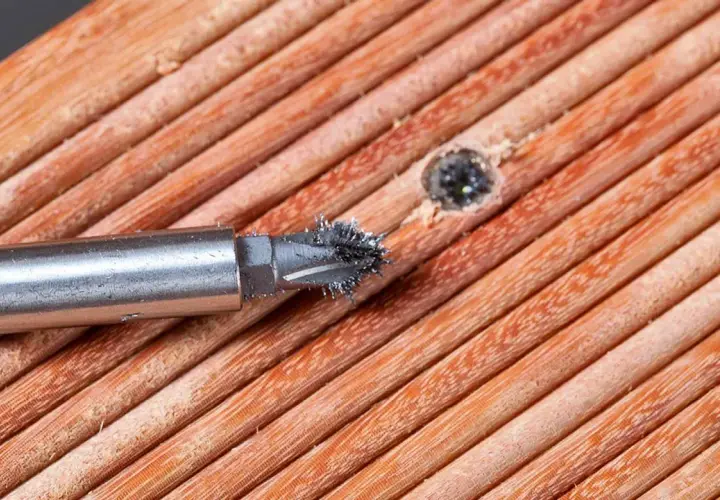 Ein Schraubenextraktor mit Metallspänen auf Holzoberfläche.