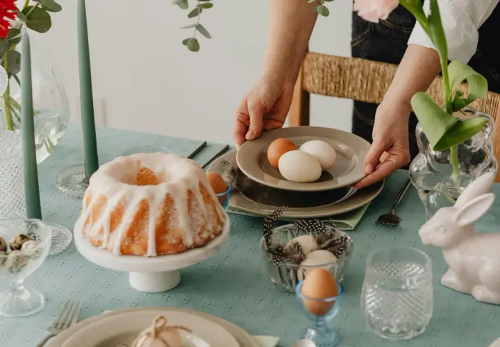 Tavola apparecchiata per Pasqua con un ciambellone glassato, uova e decorazioni. I dolci pasquali sono pronti per essere gustati.