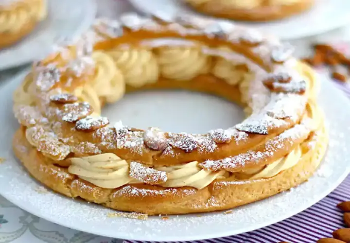 Un Paris-Brest, pâtisserie en forme de couronne, garni d'une crème onctueuse et saupoudré d'amandes effilées et de sucre glace.