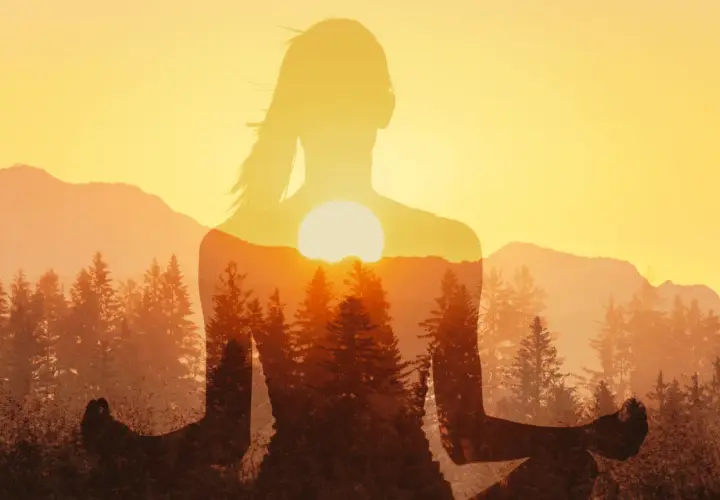 Silhouette di donna in meditazione con tramonto e foreste. Un'immagine che ispira a come ridurre lo stress con la natura.