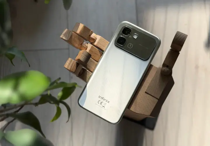 Srebrny smartfon Infinix, marka znana z innowacyjnych rozwiązań, prezentuje się na drewnianej dłoni.