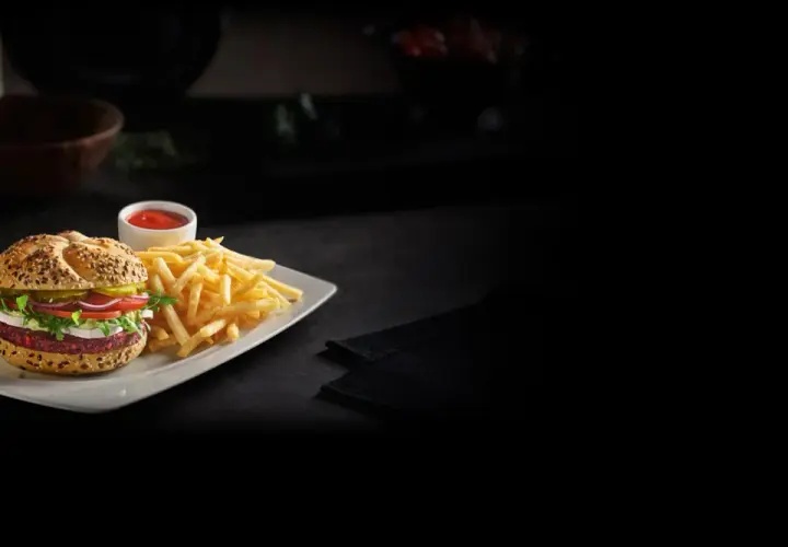 Pyszny, wegetariański konkret burger z Orlenu, podany z chrupiącymi frytkami i ketchupem. Idealny na szybki posiłek.