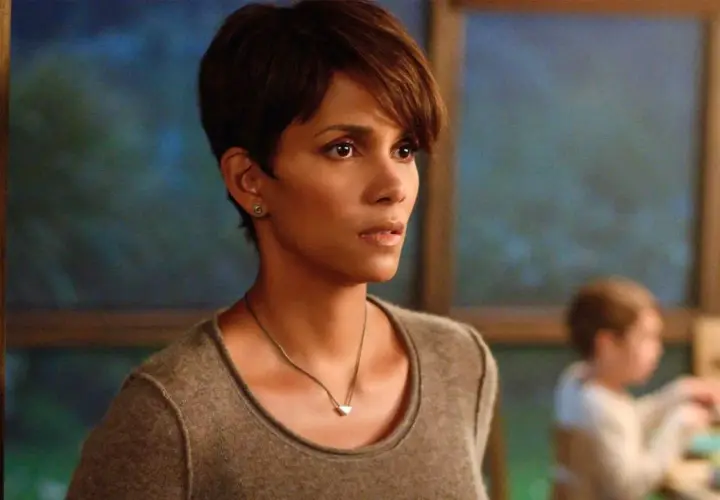 Halle Berry w filmie, zamyślona, w tle niewyraźne dziecko.