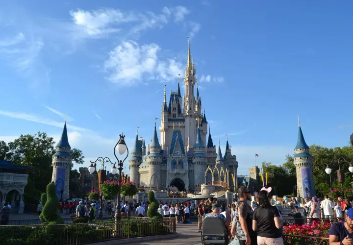 Tłum ludzi spaceruje przed zamkiem w Disneylandzie, gdzie marzenia stają się rzeczywistością.
