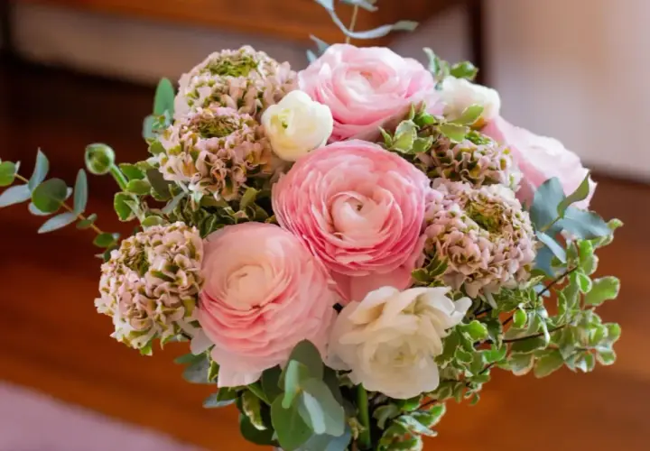 Un bouquet de fleurs roses et blanches, composé de renoncules et d'hortensias, prêt à être ajouté à la liste de souhaits du fleuriste.
