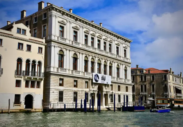 Le **Palazzo Grassi** à Venise, majestueux édifice blanc, se reflète dans le Grand Canal. Une exposition Irving Penn y est annoncée.