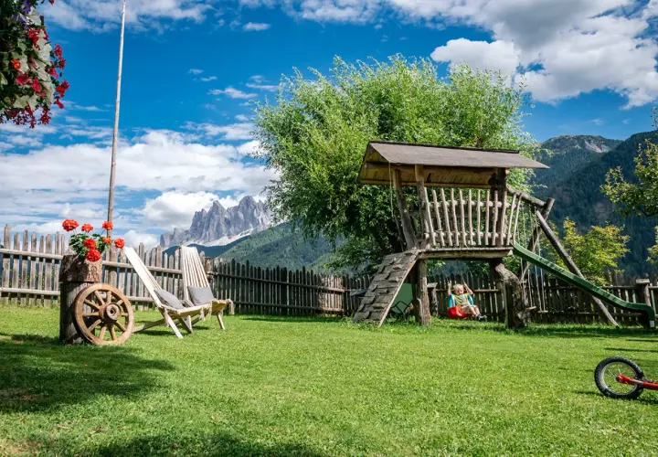 Giardino con altalena e montagne sullo sfondo, ideale per agriturismi con gallo rosso.