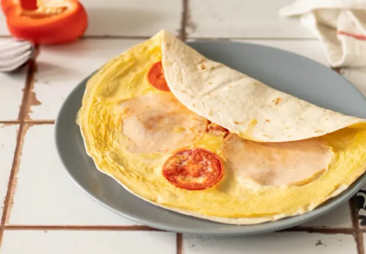 Pyszna tortilla z jajkiem, pomidorem i szynką, gotowa do zjedzenia.