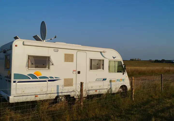Camping-car blanc stationné dans un champ en Angleterre, avec Stonehenge à l'horizon.