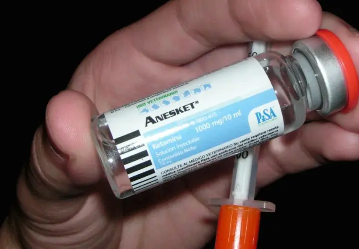 Mano che tiene una fiala di Anesket (ketamina) con siringa, suggerendo potenziali ketamina effetti positivi in contesti medici.