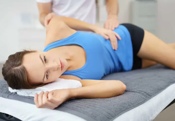 Fizjoterapeuta masuje kobietę z zapaleniem kaletki, łagodząc ból.