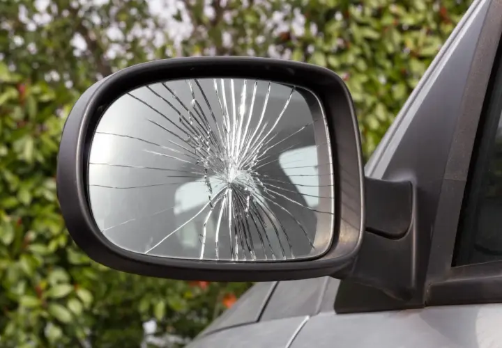 Specchietto rotto dell'auto, con il vetro frantumato in mille schegge che riflettono la luce.