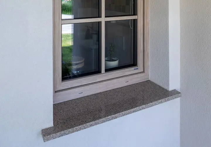 Kamienny parapet zewnętrzny wystaje ok. 5 cm, chroniąc elewację. Idealna proporcja, by wiedzieć, ile powinien wystawać parapet zewnętrzny.