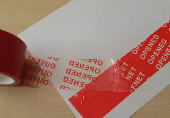 Czerwona taśma konturowa z napisem "OPENED" i "OUVERT" zabezpiecza biały papier.
