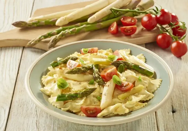 Pyszne szparagi na obiad w kremowym sosie z makaronem farfalle, pomidorkami i bazylią.