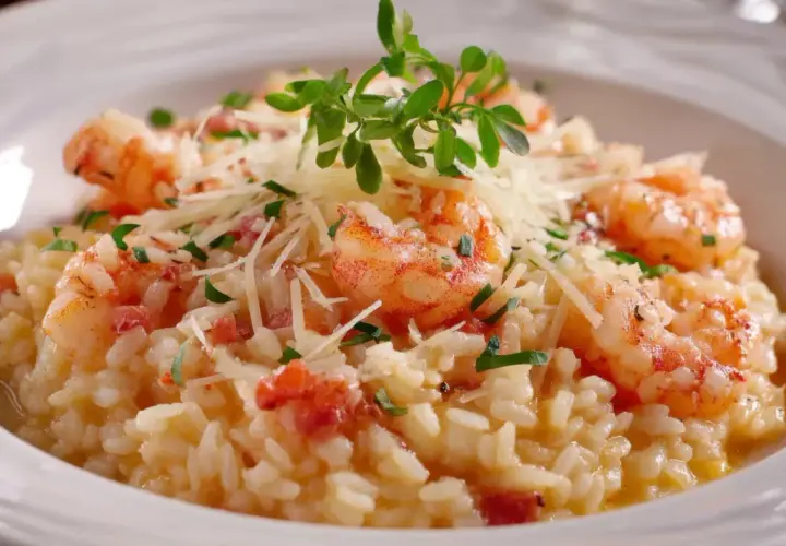 Un crémeux risotto au gambas, garni de parmesan râpé et d'une touche de verdure fraîche. Un délice pour les yeux et les papilles.
