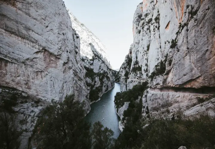 El río serpentea entre imponentes paredes rocosas en el congost de Montrebei. Pequeñas embarcaciones navegan tranquilamente por sus aguas.
