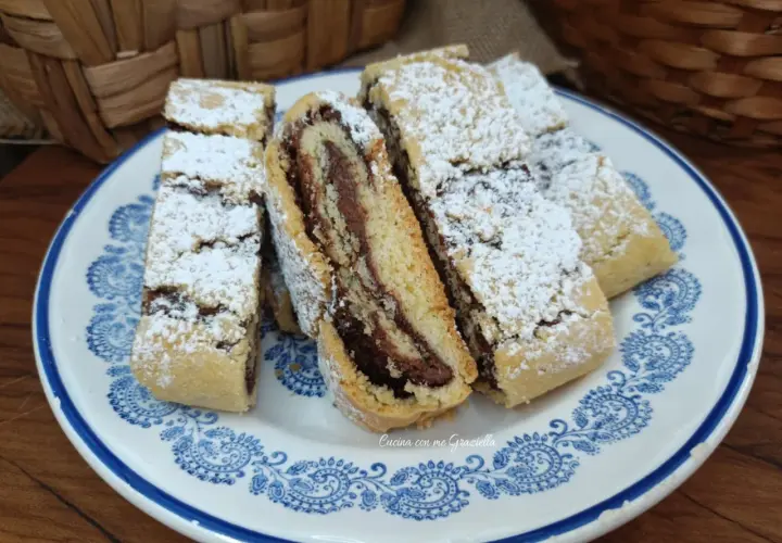 Fette di biscotti della nonna con ripieno di crema al cioccolato, spolverati di zucchero a velo, su un piatto decorato.