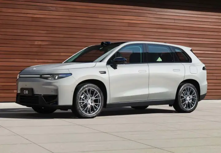 Elegante auto elettrica Leapmotor C10 color argento metallizzato, con un design moderno e linee aerodinamiche, parcheggiata davanti a una parete di legno.