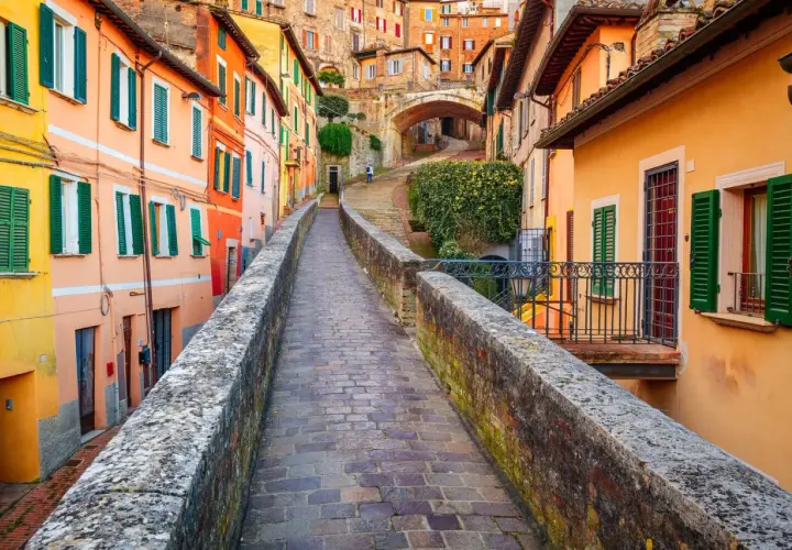 Un vicolo pittoresco a Perugia, con case colorate e un ponte in pietra. Perfetto per scoprire le cose da fare a Perugia.