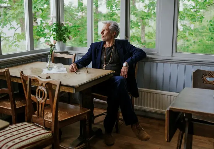 Carl-Johan Vallgren, med sin fru vid sin sida, sitter vid ett bord med utsikt över en grönskande trädgård.