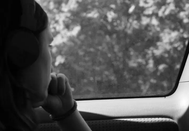 Ragazza con cuffie guarda fuori dal finestrino, persa nei suoi pensieri, come in un loop di depressione, ripetere sempre le stesse cose.