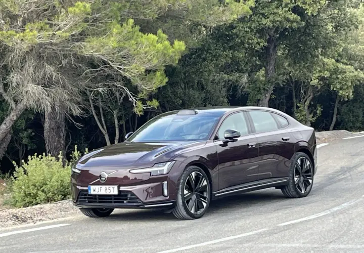 Elegancki, ciemnobrązowy Volvo ES90 na krętej drodze wśród zieleni.