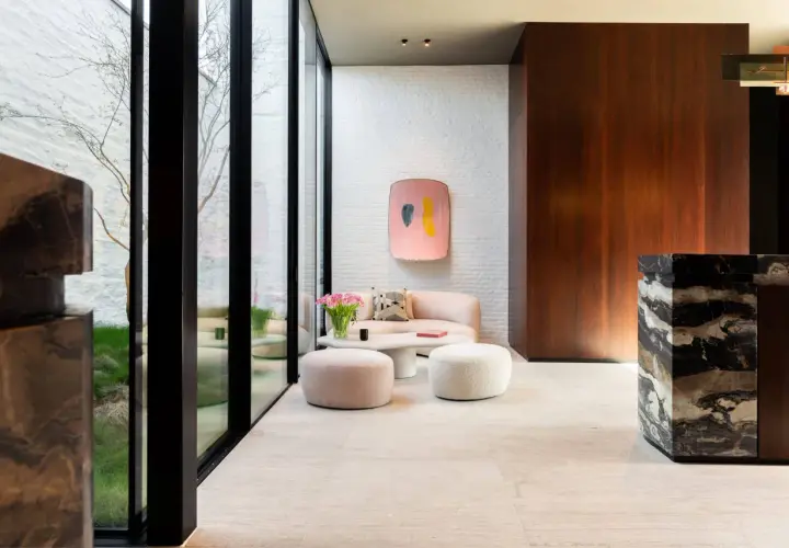 Un elegante soggiorno con pavimenti in marmo moderni, divano rosa, pouf e un tavolino bianco.