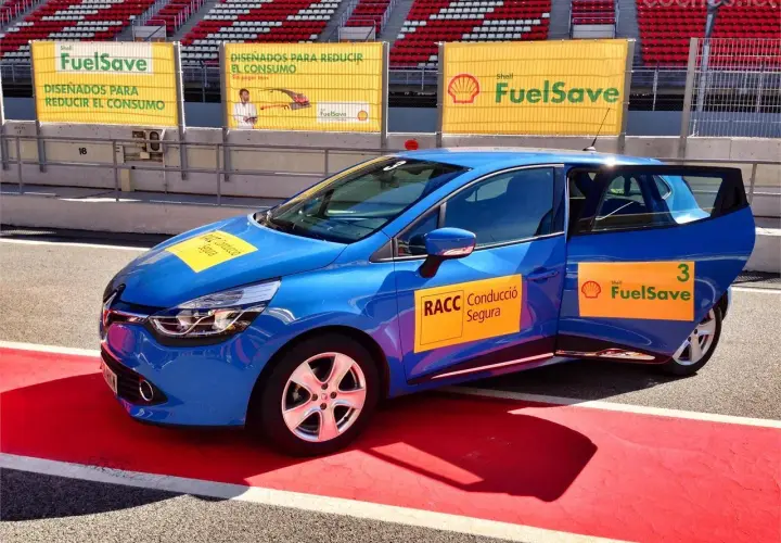 Coche azul en circuito con pegatinas Shell FuelSave, promocionando conducción eficiente.