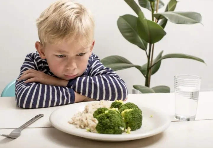 Un enfant boude devant son assiette de riz et brocolis. Une vraie galère pour trouver une idée repas enfant difficile à satisfaire !
