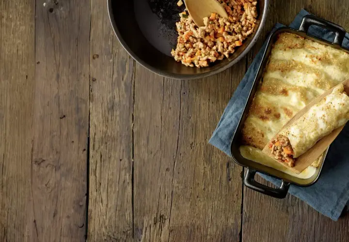Préparation d'une recette cannelloni viande hachée et béchamel : viande cuisinée dans une poêle, cannelloni garni sur une spatule, plat gratiné au fromage.